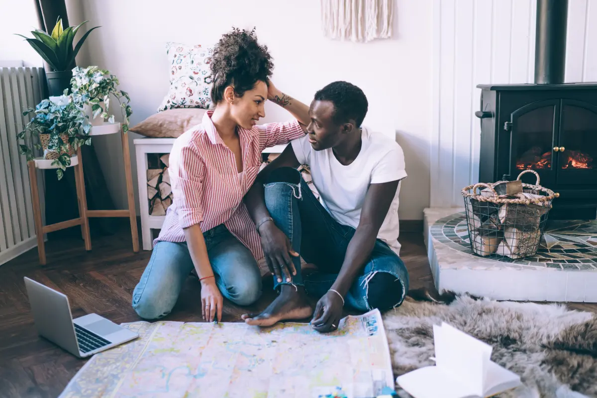 Couple Sitting On The Floor Reviewing Plans And Notes Together While Organizing Their Wedding Step By Step