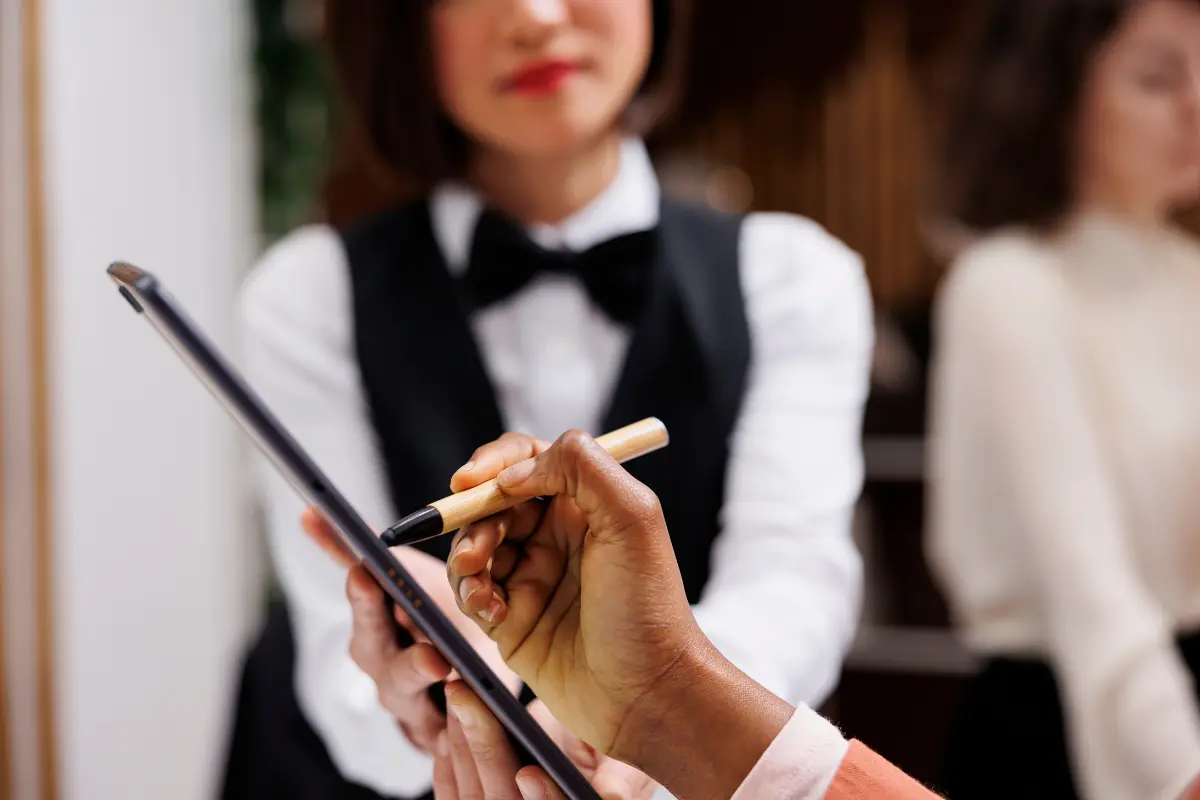 Guest Completing Paperwork At The Reception Desk As Part Of Coordinated Wedding Logistics And Event Flow